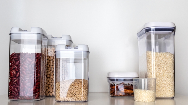 Assorted grains, nuts, and beans in plastic containers.