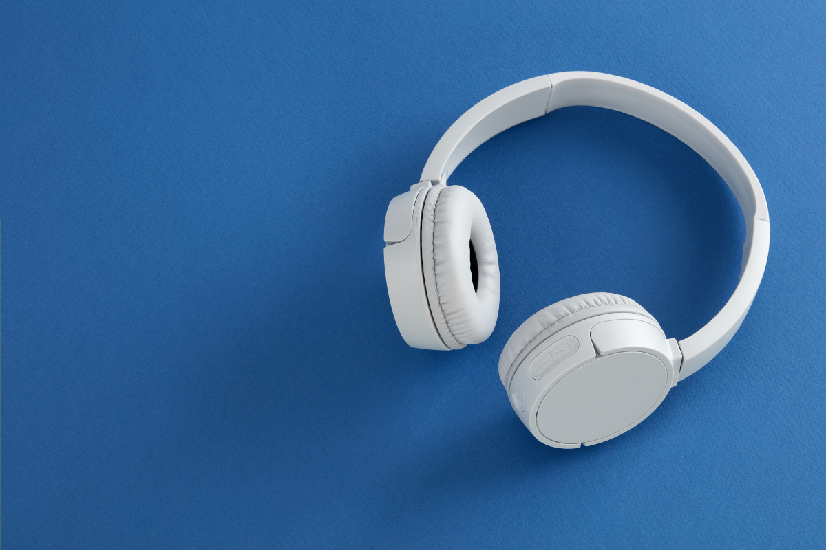 White over-ear headphones placed on a blue background, showcasing a clean and modern design.