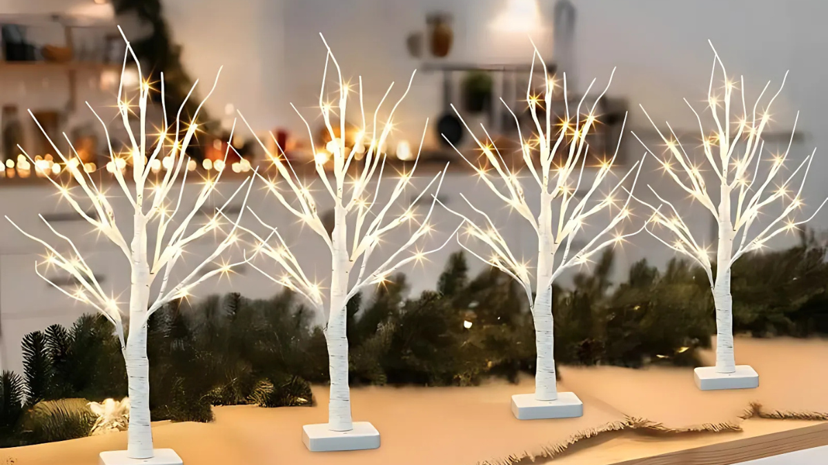 A charming arrangement of four white artificial trees illuminated with twinkling lights, creating a festive and cozy ambiance. Set against a warmly lit background, these trees add a magical touch to the holiday decor.