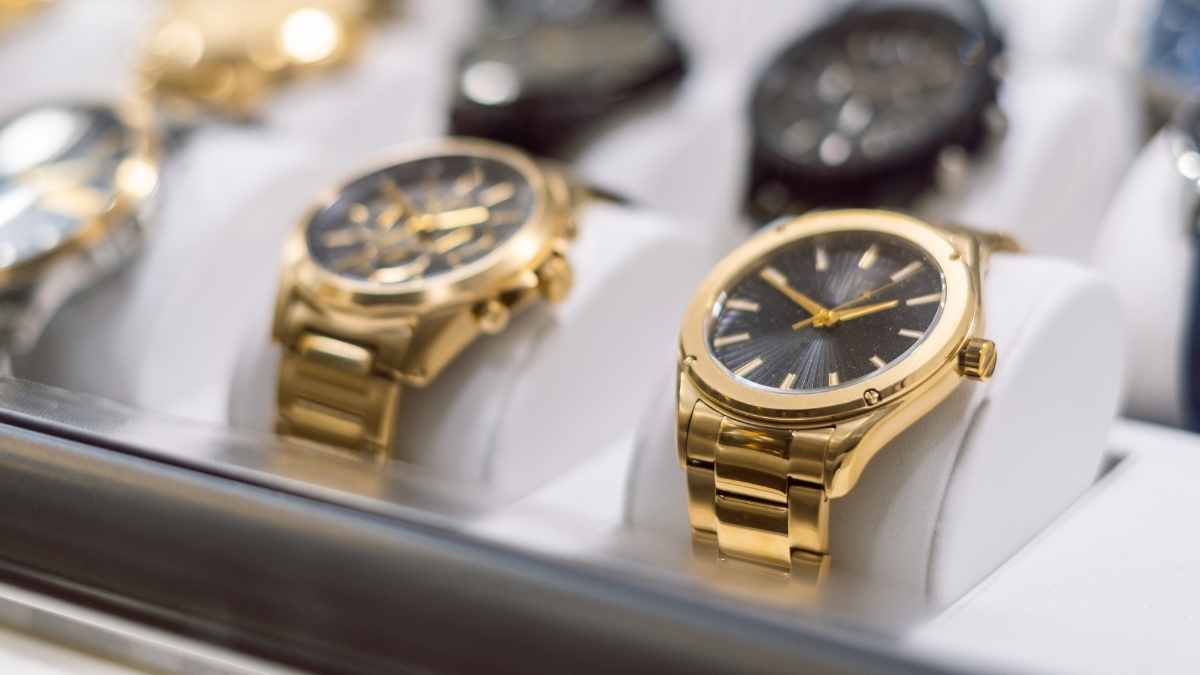 Gold luxury wristwatches displayed in a showcase with black dials and polished metal bracelets.
