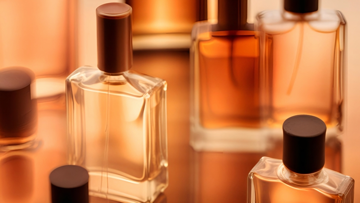 Assorted amber-toned perfume bottles arranged on a reflective surface, showcasing elegant fragrance packaging for women’s scents.